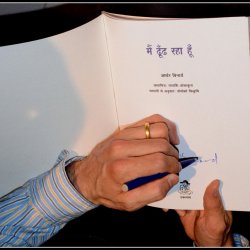 Poet Arthur Binard signing a copy of his book Main Dhoondh Raha Hoon